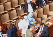 Марешки и заместничката му със защитни костюми и скафандри в парламента