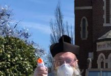 Свещеник пръска светена вода с воден пистолет, за да спази дистанцията