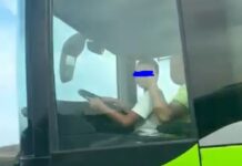 Момченце седи в скута на шофьор на автобус, пълен с пътници