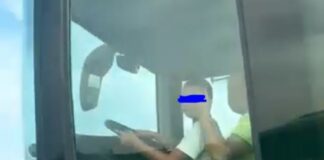 Момченце седи в скута на шофьор на автобус, пълен с пътници